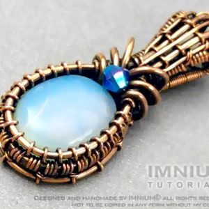 Op de afbeelding: Een hanger van koperdraad met een lichtblauwe ovale steen en een blauwe kristallen accent. De hanger heeft een geweven ontwerp en is bevestigd aan een koperen draadlus.