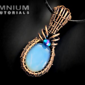 Op de afbeelding: Een hanger van gewikkeld koperdraad met een lichtblauwe ovale edelsteen en een klein iriserend blauw kristal. De hanger hangt aan een zwart koord.