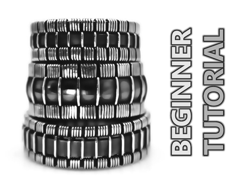 Op de afbeelding: Een stapel van vijf zilveren en zwarte armbanden met een geometrisch patroon. De armbanden zijn op elkaar gestapeld en verticaal gerangschikt. De armbanden zijn gemaakt van metaal en hebben een glanzende afwerking. De achtergrond is wit. BEGINNERSHANDLEIDING