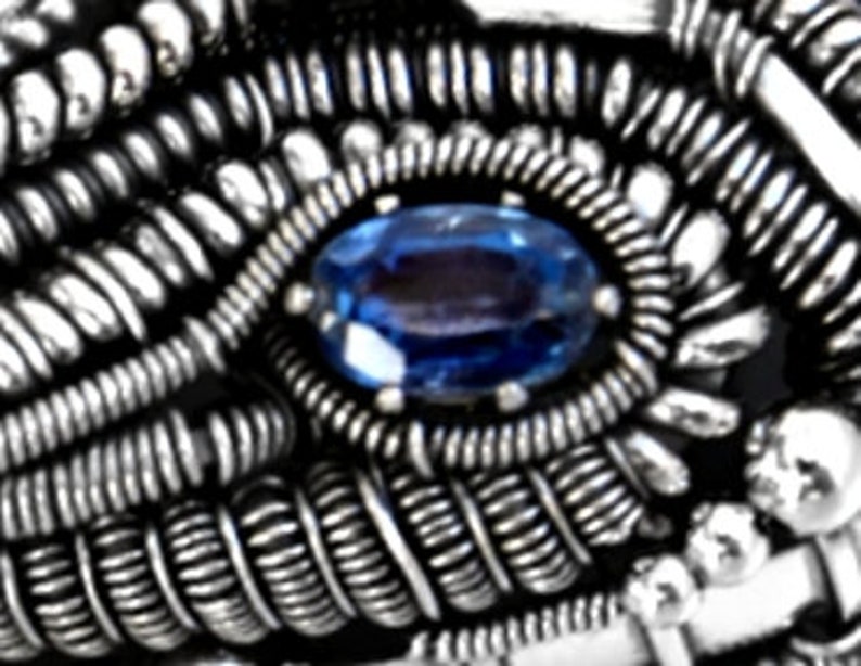 Peut inclure: Gros plan sur une bague en fil d'argent avec une pierre pr&eacute;cieuse bleue au centre.