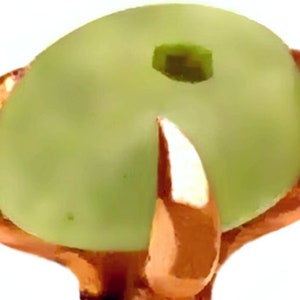 Peut inclure: Un cabochon en verre vert clair avec une monture en cuivre. Le cabochon est serti dans une monture &agrave; griffes avec quatre griffes.