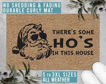 May include: A brown coir doormat with the text "There's some HO'S in this house" and a cartoon image of Santa Claus wearing sunglasses. The mat is available in sizes S to 3XL and is suitable for all weather.