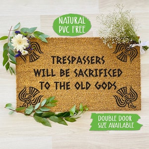 Puede incluir: Una alfombra de coco marrón con el texto "TRESPASSERS WILL BE SACRIFICED TO THE OLD GODS" en negro. La alfombra tiene un diseño natural, libre de PVC y está disponible en tamaño de doble puerta.