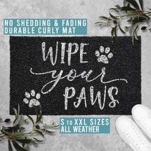Könnte beinhalten: Schwarze Fußmatte mit weißem Text, der "Wipe your paws" lautet. Die Fußmatte hat eine lockige Textur und ist aus strapazierfähigem Material gefertigt. Sie ist in Größen von klein bis extra extra groß erhältlich und für alle Wetterbedingungen geeignet.