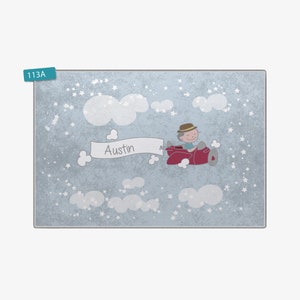 May include: A blue and white personalized nursery rug with a cartoon illustration of a boy flying a red airplane in the clouds. The rug has the name "Austin" on it.