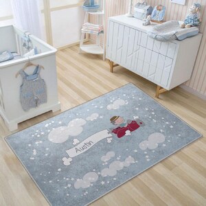 May include: A blue and white nursery rug with a cartoon airplane and clouds. The rug has the name "Austin" written on it.