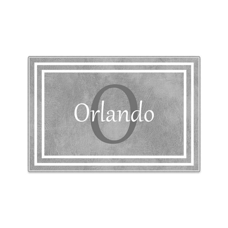 May include: Gray doormat with a white border and the letter "O" in the center. The text "Orlando" is written below the letter.