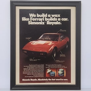 May include: Framed advertisement for Simoniz Royale wax, featuring a red sports car. The text reads, "We build a wax like Ferrari builds a car." The ad includes product images and additional text about the wax's benefits.