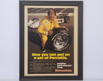 May include: Framed vintage advertisement featuring a race car driver in a yellow racing suit holding a Firestone tire. The ad text reads "Now you can put on a set of Parnelli's" and promotes Firestone tires.