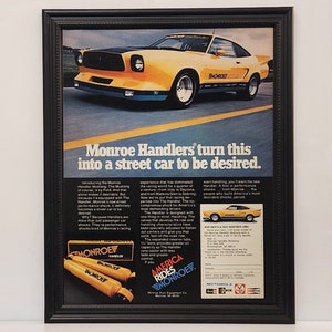 May include: A vintage advertisement for Monroe Handlers shock absorbers featuring a yellow 1970s Ford Mustang with the text "Monroe Handlers turn this into a street car to be desired." The ad highlights the performance and handling capabilities of the shocks.