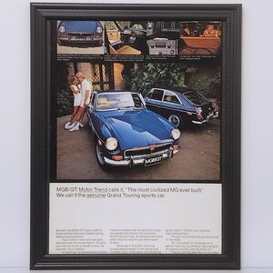 May include: Framed vintage advertisement featuring a blue MG sports car. The ad includes images of the car's interior and exterior, with text that reads "MGB/GT. Motor Trend calls it, 'The most civilized MG ever built.' We call it the genuine Grand Touring sports car."