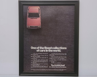 May include: A vintage advertisement for the Audi 100LS. The ad features a red car against a dark gray background. The text reads "One of the finest collections of cars in the world." and "The $3,900 Audi. It's a lot of cars for the money."