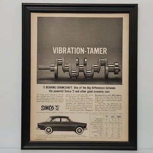 May include: Framed vintage advertisement for the Simca 5 car, featuring a crankshaft and the text "VIBRATION-TAMER." The ad highlights the car's features with a diagram and a picture of the vehicle. The frame is black.