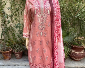 May include: A pink and white cotton salwar kameez with intricate embroidery and paisley patterns. The outfit includes a long-sleeved top, pants, and a matching dupatta.