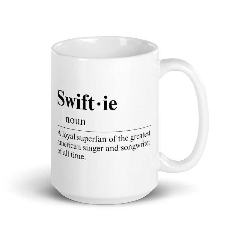May include: White ceramic coffee mug with a black design that reads "Swift.ie noun A loyal superfan of the greatest american singer and songwriter of all time."