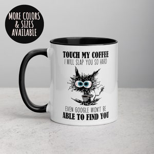 May include: White ceramic coffee mug with a black rim and handle. The mug features a black and white illustration of a cat with large eyes holding a cup of coffee. The text on the mug reads "Touch my coffee I will slap you so hard even Google won't be able to find you."