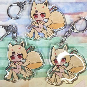 May include: Four keychains featuring a cartoon fox character with red eyes, tan fur, and a bell. The fox is holding a staff and has a fluffy tail. Each keychain has a silver metal clasp.