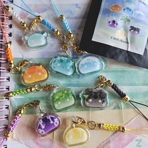 Puede incluir: Un conjunto de 10 amuletos de Slime de Genshin Impact, cada uno con un tipo de slime diferente. Los amuletos están hechos de plástico transparente con un diseño de slime colorido en el interior. Los amuletos están unidos a cordones de cuerda coloridos con cierres dorados. Los amuletos miden 2,5 cm.