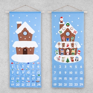 Puede incluir: Un calendario de adviento de fieltro azul con forma de casa de jengibre con 24 bolsillos numerados. La casa tiene un techo blanco y detalles marrones. Hay pequeñas decoraciones de fieltro en la casa, incluyendo bastones de caramelo, una estrella y un corazón. Los números del 1 al 24 están impresos en los bolsillos.