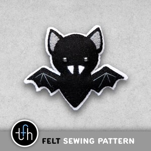 May include: A black felt bat with white trim and silver accents. The bat has outstretched wings and a smiling face. The image includes the text "FELT SEWING PATTERN" and a logo.