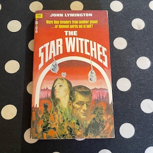 May include: A vintage paperback book titled "The Star Witches" by John Lymington. The cover features a red background with white text and illustrations of a man and woman. The book's cover also includes the text: "Were they invaders from another planet...or damned spirits out of hell?"