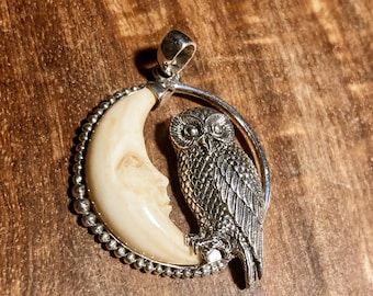 May include: A silver pendant featuring a carved ivory crescent moon with an owl perched on the edge. The owl is detailed with intricate feathers and has a realistic appearance.