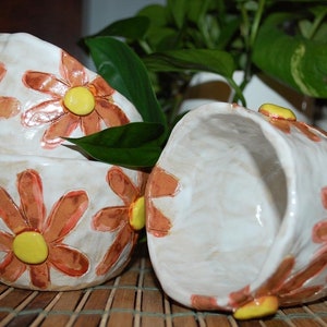 May include: Three white ceramic bowls with a floral design. The bowls are decorated with orange and yellow flowers. The bowls are stacked on top of each other.