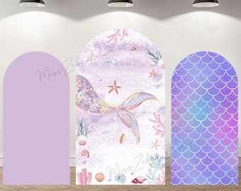 May include: Three arched panels for a mermaid-themed event. The center panel features a mermaid tail with a watercolor background, starfish, and coral. The panel on the right has a scale pattern. The left panel is solid lavender. The text "Miss Zebra Studios" is visible.