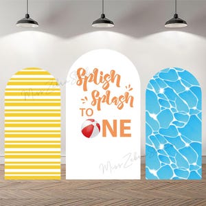 May include: Three arched backdrop panels. The left panel features horizontal yellow and white stripes. The center white panel displays the orange text "Splish Splash TO ONE" with a red and white beach ball. The right panel shows a blue water pattern.