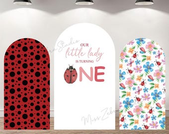 May include: Three arched backdrop panels for a first birthday celebration. One panel features a red ladybug pattern, another has the text "Our little lady is turning ONE" with a ladybug graphic, and the third displays a floral and ladybug design.