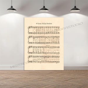 May include: A framed print of sheet music, featuring the hymn "O Come All Ye Faithful." The music is printed on aged, cream-colored paper, with black musical notes and text. The print is displayed on a white wall with a wooden floor.
