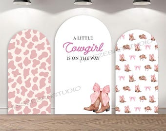 May include: Three white arched panels with a western theme. One panel has a pink cow print, the center panel reads "A Little Cowgirl Is On The Way" in pink text, and the third panel has a pattern of cowboy boots, hats, and bows.