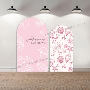 Peut inclure: Deux fonds d'arche pour une baby shower. L'un est rose avec des illustrations de coquillages blancs et le texte "Alessia's BABY SHOWER". L'autre est blanc avec des illustrations de coquillages et de nœuds roses.