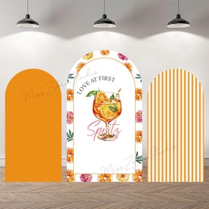 Może przedstawiać: Trzy łukowate panele tła. Centralny panel przedstawia akwarelową ilustrację koktajlu Aperol Spritz ze słowami "Love at First Spritz". Pozostałe panele są w jednolitym pomarańczowym kolorze oraz w pomarańczowo-białe paski.