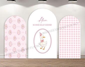 May include: A three-panel backdrop with a whimsical theme. The center panel features a goose illustration with the text "Alice is one silly goose!". The side panels have a pink floral and gingham pattern. The backdrop is set against a wooden floor.