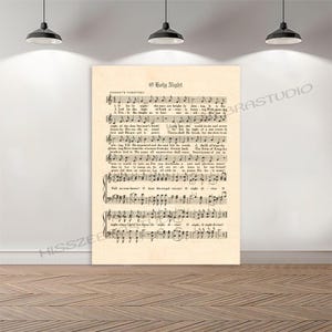 May include: A framed print of sheet music for "O Holy Night" in a vintage style. The text is in black ink on aged, cream-colored paper. The print is displayed on a white wall, illuminated by overhead lights.