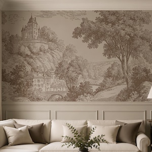 May include: A living room with a neutral color palette, featuring a large sectional sofa, two armchairs, and a dark wood coffee table. The focal point is a scenic wallpaper depicting a landscape with castles and trees. A lamp and framed artwork add to the decor.