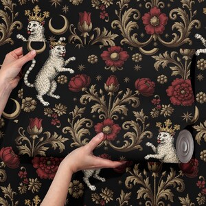 May include: Black wallpaper featuring a repeating pattern of gold scrollwork, red flowers, and crowned white cats. The wallpaper is being unrolled, showcasing the design. The overall theme is a whimsical, vintage aesthetic.