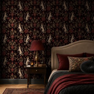 May include: A bedroom featuring a dark burgundy wallpaper with a repeating pattern of white cats, flowers, and moons. A red lampshade sits on a wooden bedside table next to a bed with burgundy and black bedding.