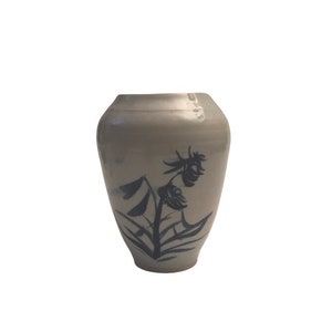 May include: A gray ceramic vase with a blue floral design. The vase is round and has a wide mouth.
