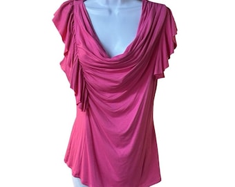 May include: A bright pink top with a draped cowl neckline and ruffled cap sleeves. The fabric is gathered at the neckline and drapes down the front. The top is displayed on a white mannequin.