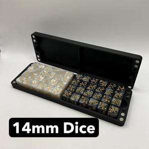 May include: Black dice case with two compartments, one filled with white and gold dice, the other with black and gold dice. The text "14mm Dice" is displayed in a black rectangle.