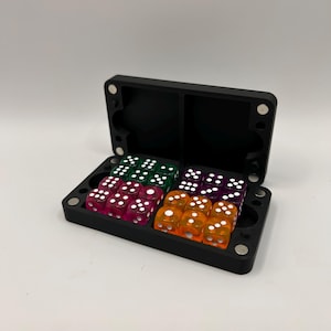 May include: A black, rectangular dice case with a magnetic closure, open to reveal several sets of colorful dice. The dice are transparent and come in various colors, including pink, green, purple, and orange, with white pips.