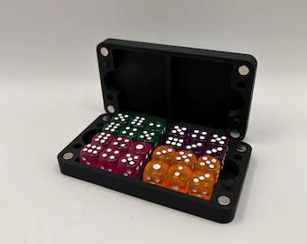 Puede incluir: Un estuche negro para dados, abierto para mostrar varios juegos de dados de colores. Los dados transparentes son rosas, verdes, morados y naranjas, con puntos blancos. El estuche es rectangular y tiene cierre magnético.