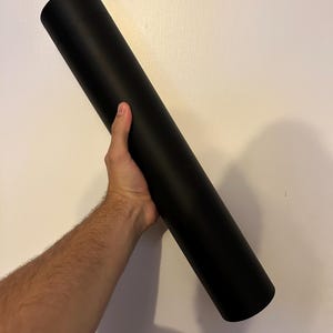 Puede incluir: Un tubo de póster negro enrollado.