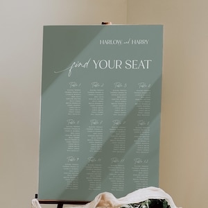 May include: A sage green wedding seating chart with white text. The chart is titled "HARLOW and HARRY find YOUR SEAT". The chart lists the names of guests assigned to each table.