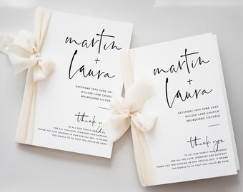 May include: Two white cards with black calligraphy text. The top card says "martin + laura" and the bottom card says "thank you" with a message of gratitude to family and friends. Both cards have a white ribbon tied around them.