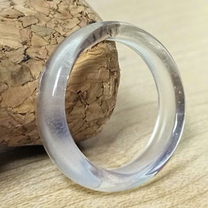 Op de afbeelding: Een transparante ring gemaakt van glas of plastic. De ring is simpel en elegant, met een gladde, gepolijste afwerking.