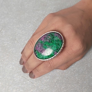 May include: A silver ring featuring a large oval green and pink gemstone.
