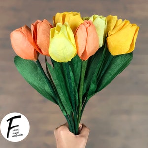 May include: A bouquet of paper tulips in shades of yellow and orange. The tulips are made of tissue paper and have a realistic appearance.